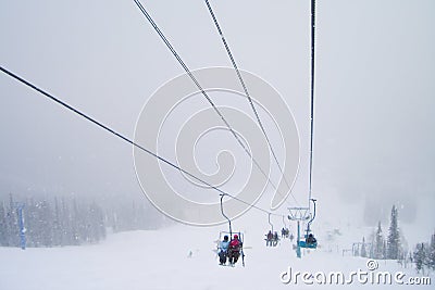 Skiers on the chairlift route while snowfall Stock Photo