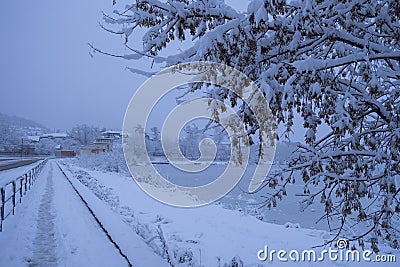 Snowfall and slippery road. Road safety in winter with snowfall. Winter cityscape. Small town street. Snow covered sidewalk. Urban Stock Photo