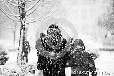 Snowing urban landscape with people passing by Stock Photo