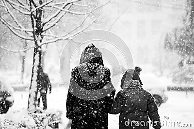 Snowing urban landscape with people passing by Stock Photo