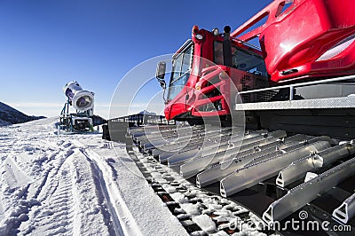 Snowmaking gun and snow groomer on ski slopes Stock Photo