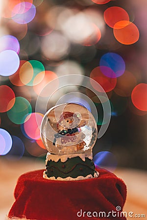 Snowman glass ball decoration with Christmas lights in the background Stock Photo