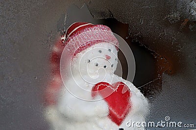 Snowman holding heart looking out window Stock Photo