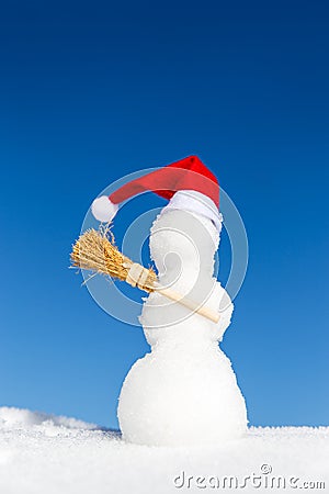 Snowman with a pointed cap and a broom in the snow Stock Photo