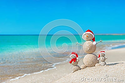 Snowmans family at sea beach in santa hat. Stock Photo