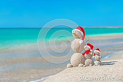 Snowmans family at sea beach in santa hat. Stock Photo