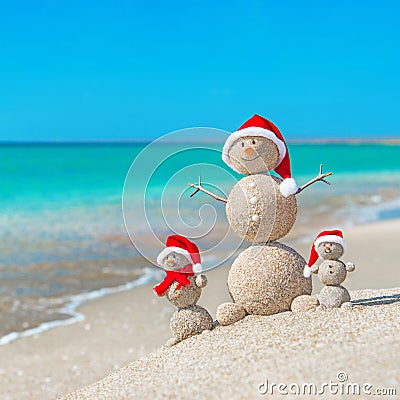 Snowmans family at sea beach in santa hat. Stock Photo