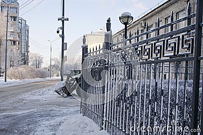 snowplow is parked near a snow-covered metal fence Stock Photo
