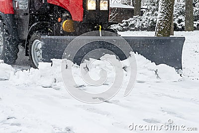 Snowplow removes snow from the sidewalk during a snowfall Stock Photo