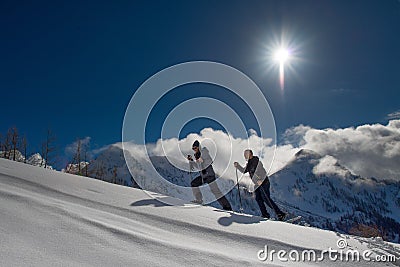 Snowshoes practiced by a boy and a girl in the warm mountain sun Stock Photo