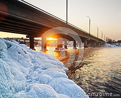Snowy bridge and beautiful frosty sunset on the river in winter Stock Photo