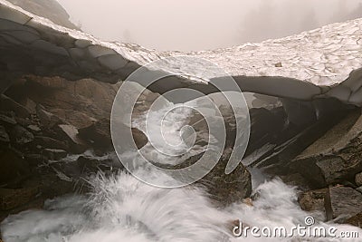 Snowy bridge over mountain creek. Stock Photo