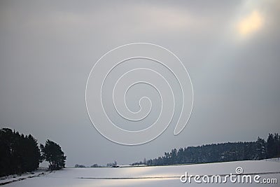 Countryside in winter by grey sky and glaring sunlight Stock Photo