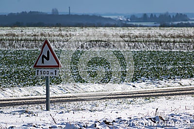 Snowy countryside landscape with sunshine and a road sign, dangerously slippery Stock Photo