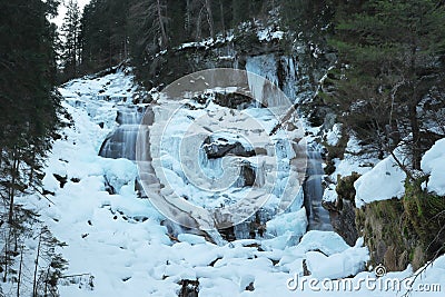 Snowy and frozen natural waterfall. Wild natural stream in winter. Slow shutter speed. Motion photography. Stock Photo