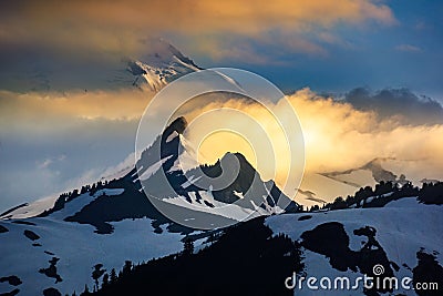 Snowy mountain and clouds illuminated by setting sun Stock Photo