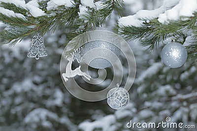 Snowy pine tree branches with sparkling reindeer ornament and Christmas baubles at wood background Stock Photo