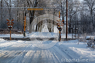 Snowy road crossing railway with sign in Swedish saying dangerous power line Stock Photo