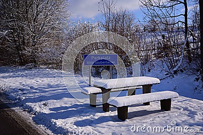 A snowy roadside rest area in Germany with tables and benches in winter, which is deserted Stock Photo