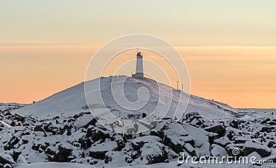 Snowy rocky mountain with Reykjanesviti lighthouse on it during sunset Stock Photo