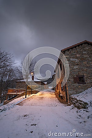 Snowy street with a street light on the sidewalk in the medieval village of La Hiruela Stock Photo
