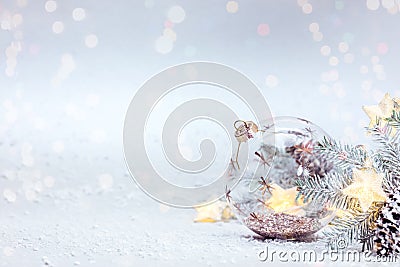 Snowy winter background with fir tree branch, glass ball and glowing lights garland Stock Photo