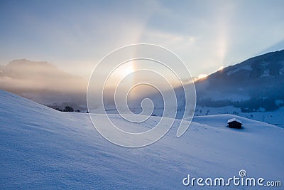 Snowy winter landscape in the alps, sunrise with halo phenomena Stock Photo