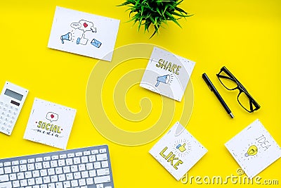 Socail media icons on work desk of marketing expert. Digital promotion of goods and services. Yellow background top view Stock Photo