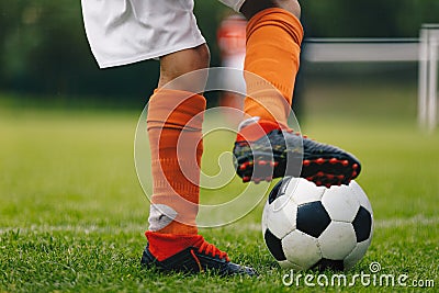 Soccer ball kick. Close up of legs and feet of football player in red socks and cleats running and dribbling with the ball Stock Photo