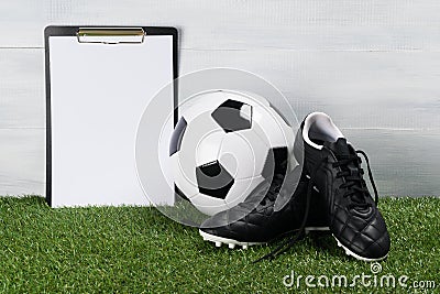 Soccer ball and shoes on the grass on a light background, a place for your inscription Stock Photo