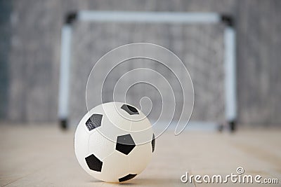 A soccer ball in a small gate on a gray background. Mini football. Stock Photo