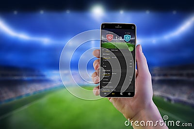 Soccer betting online app on smart phone ih man hand with football stadium Stock Photo