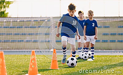 Soccer camp for kids. Boys practice dribbling in a field. Players develop good soccer dribbling skills. Children training with Stock Photo
