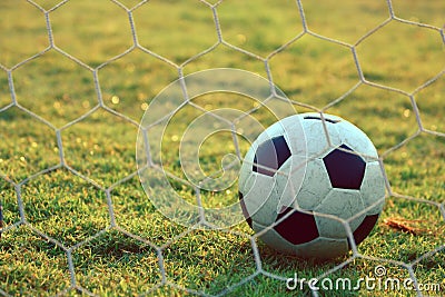 Soccer football in Goal net with green grass field Stock Photo