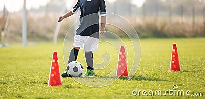 Soccer player dribbling through cones in the ground on a sunny Stock Photo