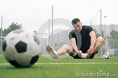 Soccer player A man holds his foot. focus on the soccer ball. Dislocation or sprain of the joint Stock Photo