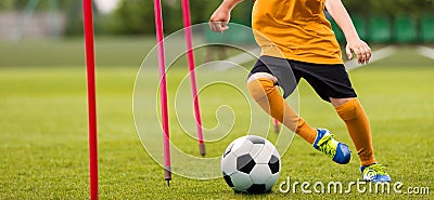 Soccer Player with Soccer Ball Running Slalom Around Training Sticks. Football Speed Training Stock Photo