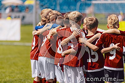 Soccer team huddling. Kids in red sportswear standing together and listening to coach Editorial Stock Photo