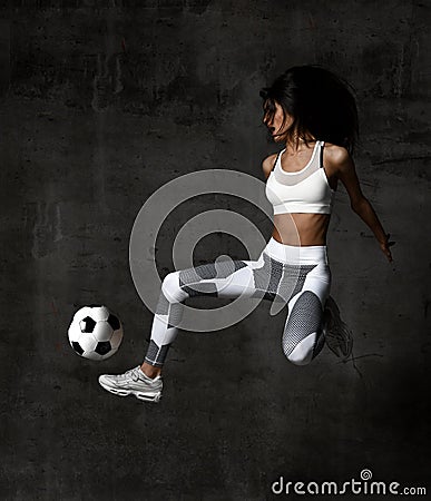 Soccer woman player jumps and hit the ball strike in the middle on concrete loft wall Stock Photo