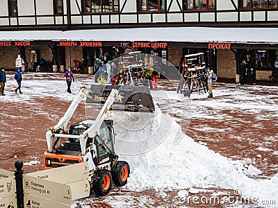 Sochi, Russia - 25 February 2020. A tractor clears snow raking it in a heap in a ski resort area Editorial Stock Photo