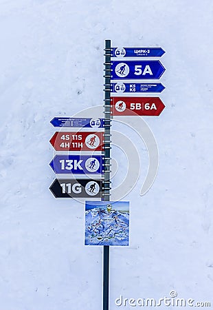 Sochi, Russia - January 7, 2018: Pole with colorful information arrows pointing directions to ski trails of different complexity i Editorial Stock Photo