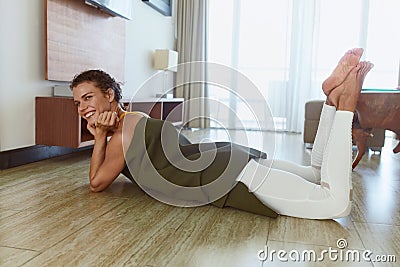 Social Isolation. Woman Wrapped In Yoga Mat After Exercising. Smiling Brunette Relaxing On Floor In Living Room After Daily Sport. Stock Photo
