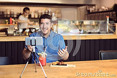 Social media influencer or food blogger creating digital marketing content by filming video inside small business restaurant Stock Photo