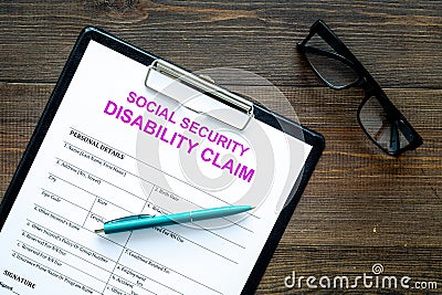 Social security. Disability claim form near glasses on dark wooden background top view Stock Photo