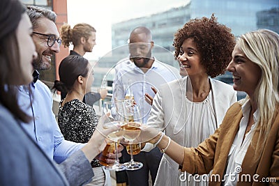 Socialising office colleagues raising glasses and making a toast with drinks after work Stock Photo