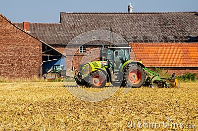 Soest, Germany - July 30, 2019: Claas arion-620 farm tractor with cultivator on the field Editorial Stock Photo