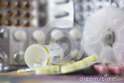 Soft blurred background with pills of various colors and shapes in blister pack, pill case, plastic jar. Stock Photo