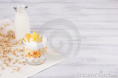 Soft breakfast with corn flakes, slice peach and milk bottle on white wood board. Decorative border with copy space. Stock Photo