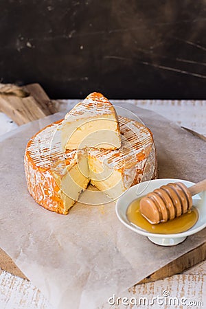 Soft cheese with cut off slice creamy texture, orange rind with mold, French, German,top view, rustic kitchen interior Stock Photo