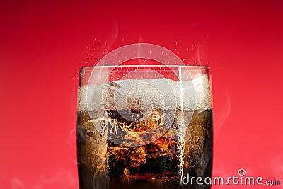 Soft drink glass with ice splash on cool smoke background. Cola glass with summer refreshment Stock Photo